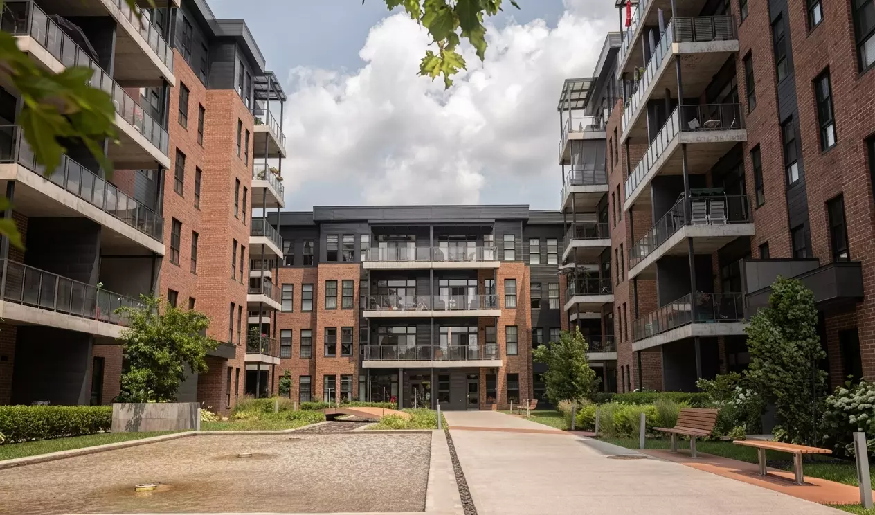 Complexe multi-logements en brique avec balcons et cour intérieure paysagée